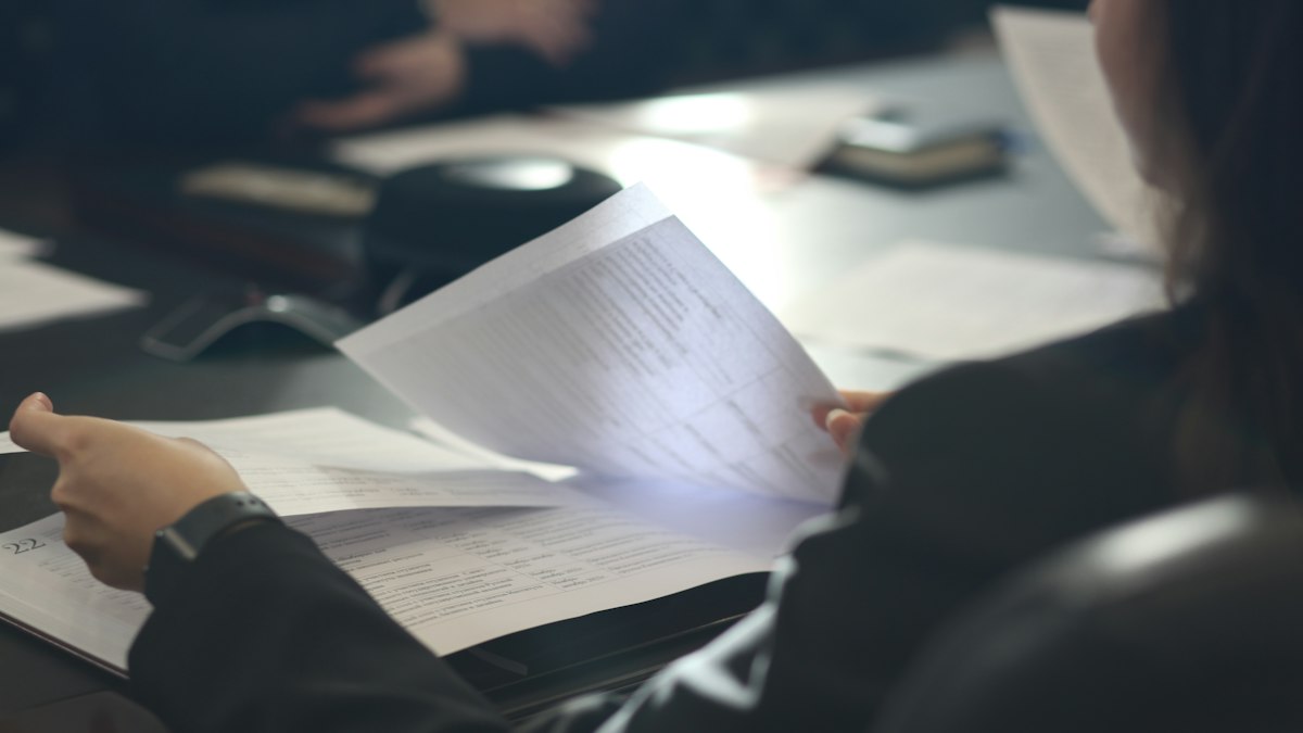 A woman at a desk reading a printed document