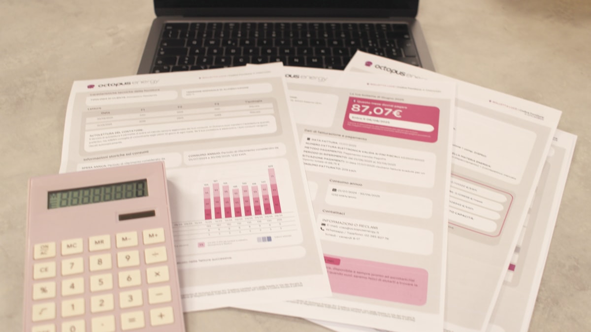 Bills, a calculator, and a laptop on a desk during bookkeeping work