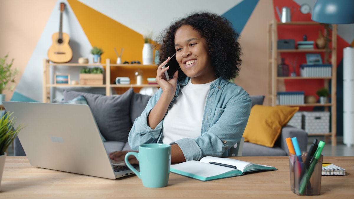 A woman at a desk on a phone call with a laptop open, reviewing quote details