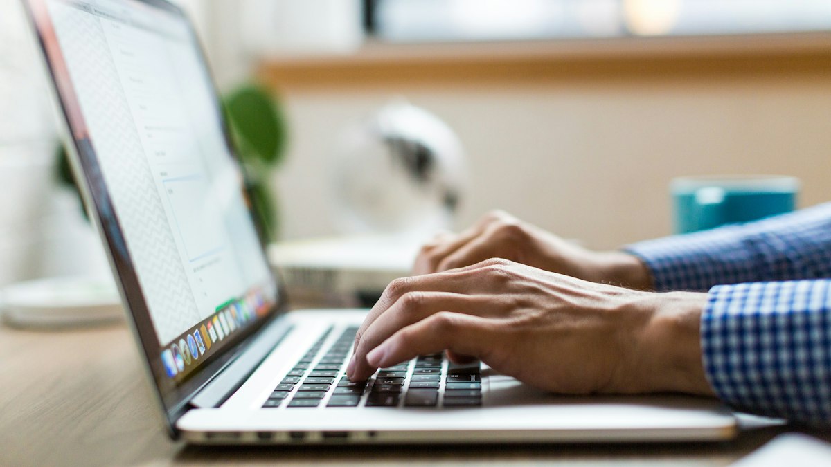 Close-up of a person's hands typing on a laptop keyboard, illustrating keyboard-only navigation of a website