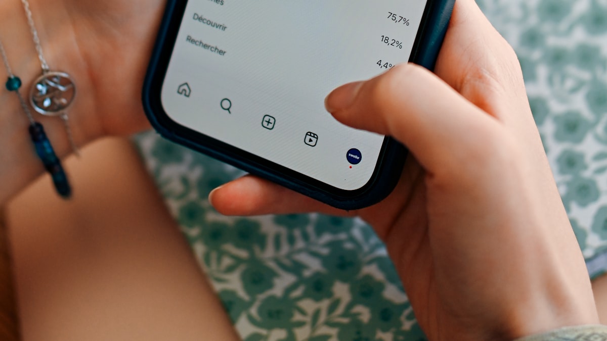 A person holding a phone and looking at social media analytics and post performance
