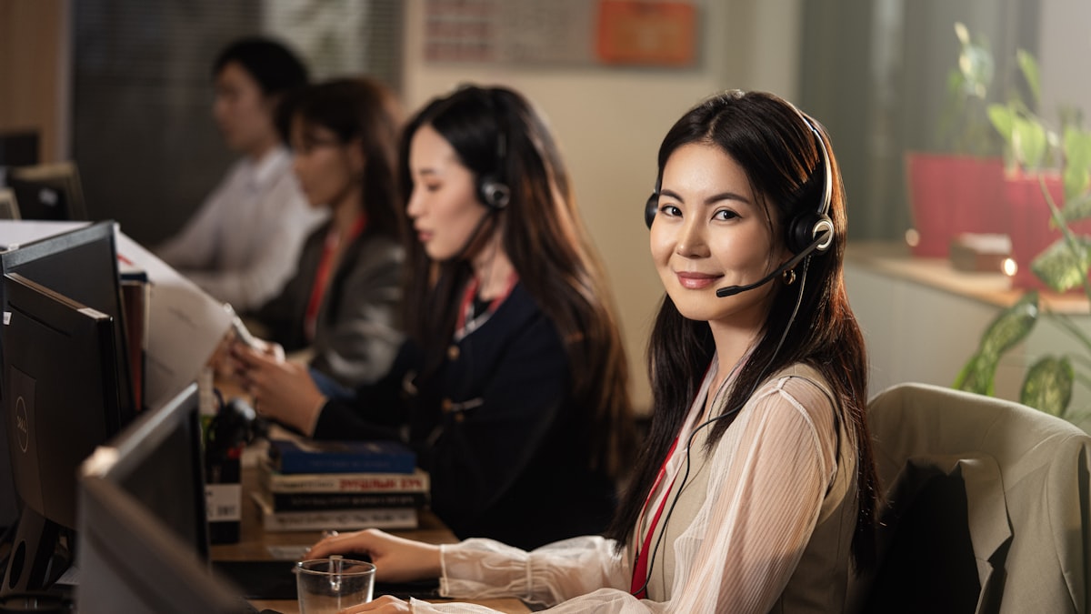 A front desk professional wearing a headset while working at a computer, representing a practice's phone line being handled alongside scheduling software