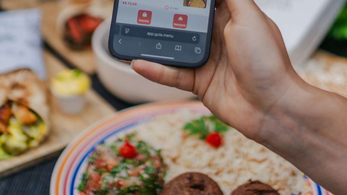 A hand holding a smartphone displaying a food ordering app screen