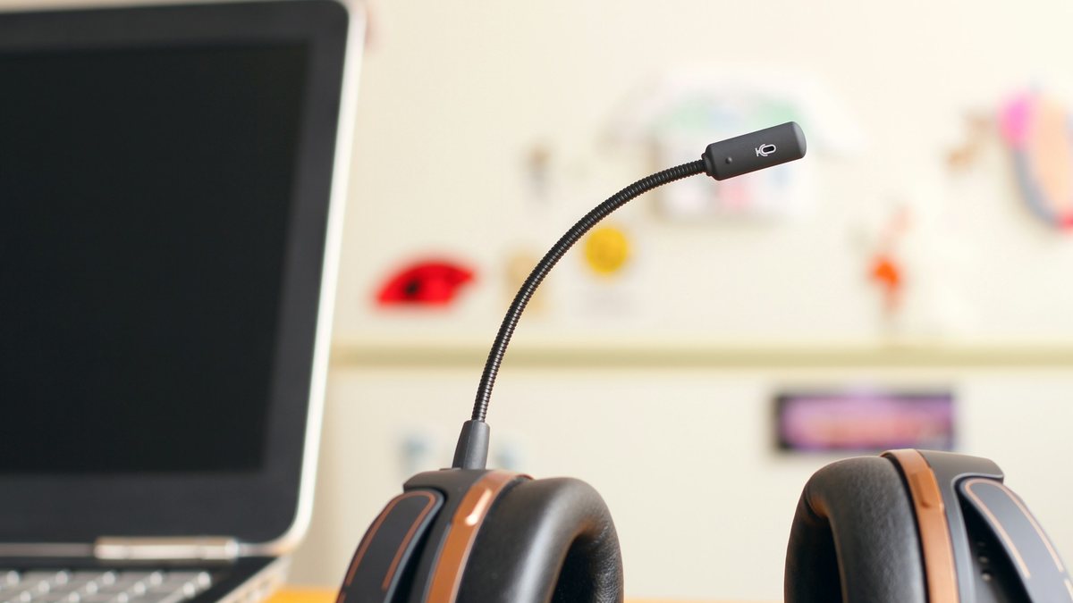 A call headset resting on a bright desk beside an open laptop, representing an AI voice agent answering business calls after hours