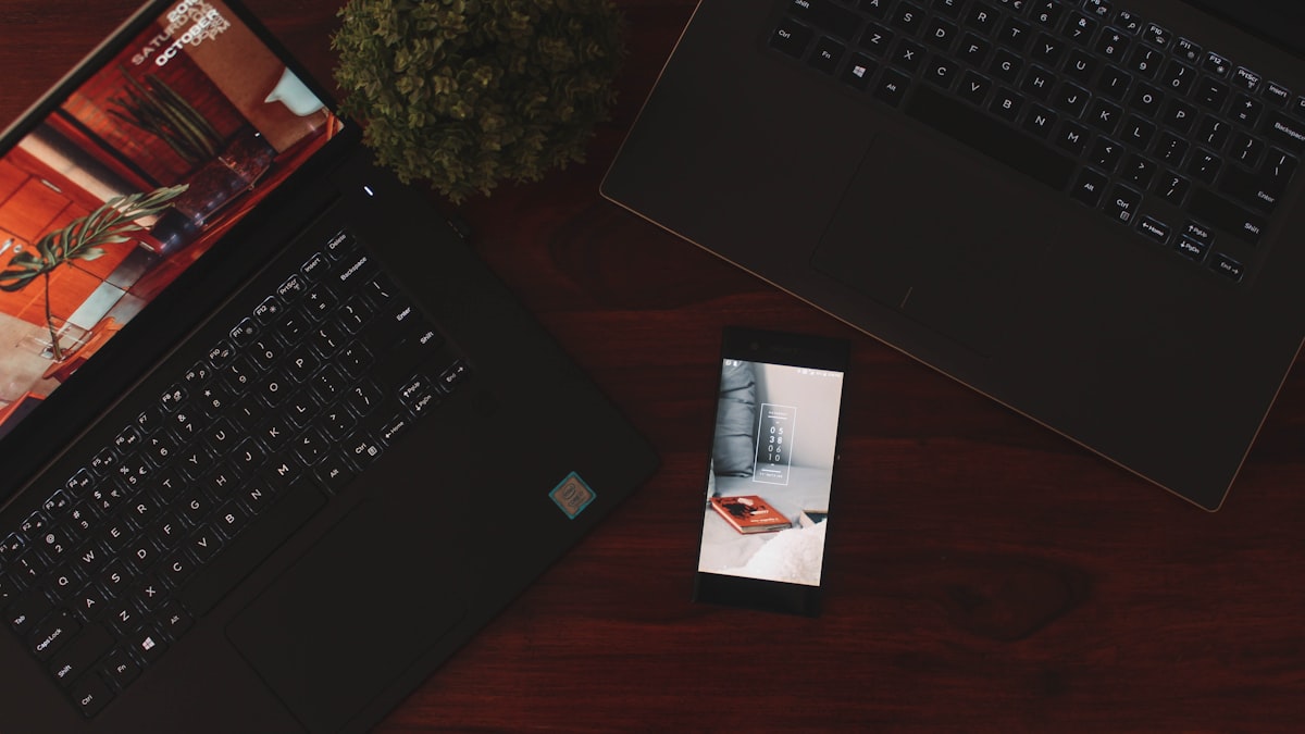 A smartphone displaying a mobile app interface resting on a laptop keyboard, representing the choice between building one cross-platform codebase or two native apps
