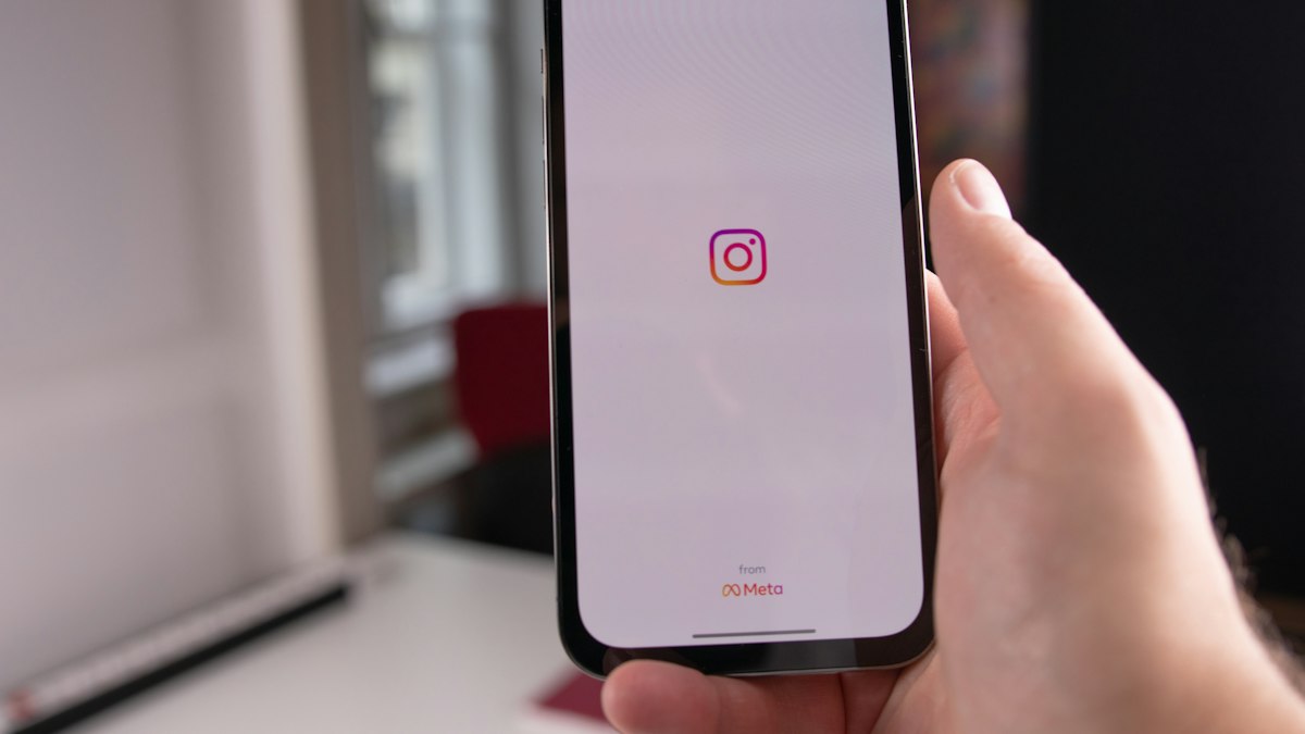 Close-up of a hand holding a smartphone with the Instagram app open, representing the kind of app a business runs a social media contest or giveaway through