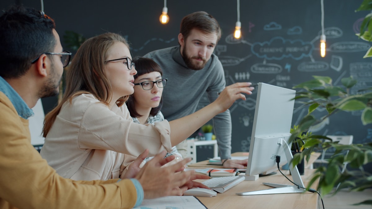 Two software developers reviewing code and a project timeline on a large monitor in an office