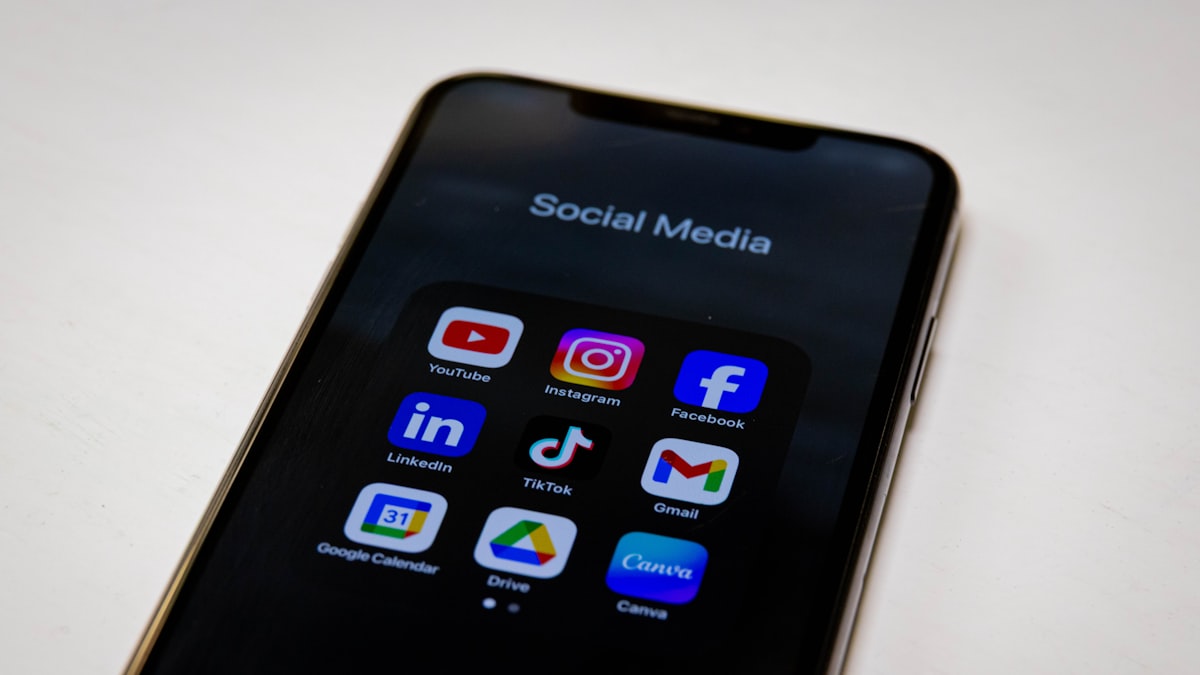 Close-up of a smartphone screen showing a folder of social media app icons including Instagram, LinkedIn, TikTok, and Facebook, representing the platforms a single blog post gets repurposed across