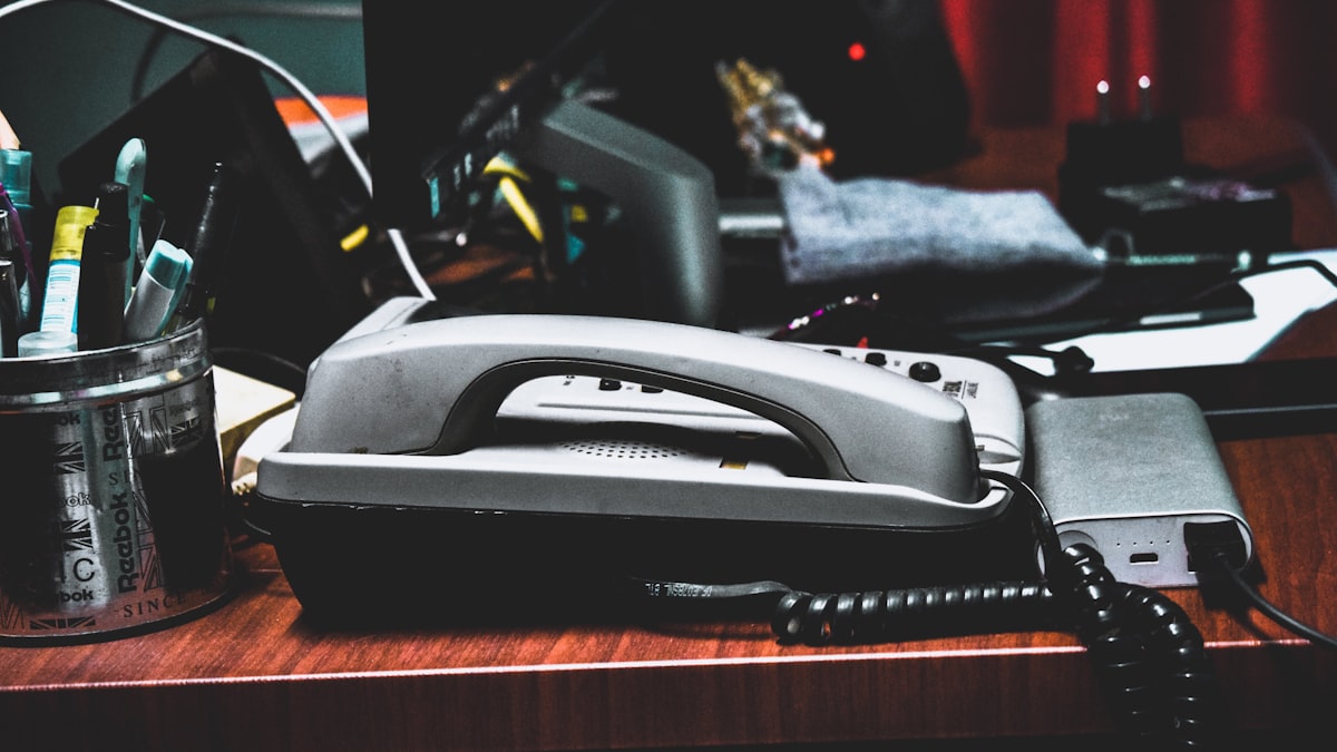 A desk phone surrounded by pens and paperwork, representing the call records and consent documentation a voice agent generates