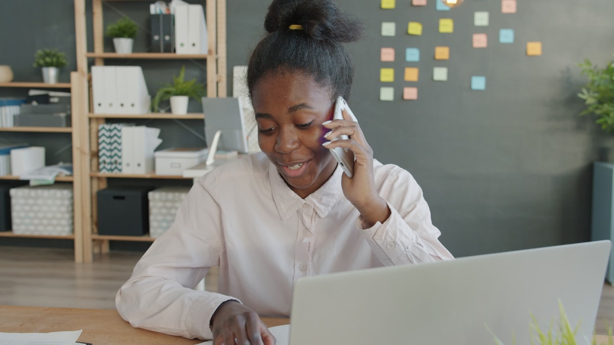 A woman at an office desk with a laptop, talking on the phone